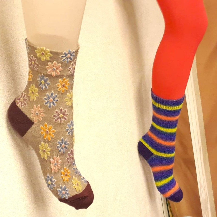 Nahaufnahme von zwei Tabio-Socken, eine mit verspieltem Blumenmuster und eine mit Streifenmuster, an Schaufensterpuppen-Beinen